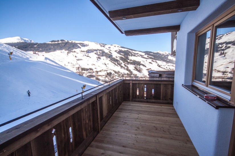 Balkon mit Blick auf die verschneiten Berge und die Skipiste