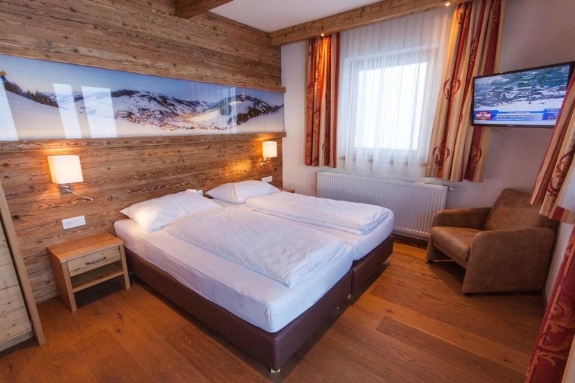 Schlafzimmer mit Doppelbett, Sessel und TV