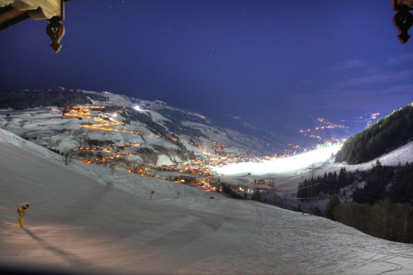 Nächtlicher Blick von der Ferienwohnung 80 ins Tal von Saalbach Hinterglemm mit beleuchteter Skipiste