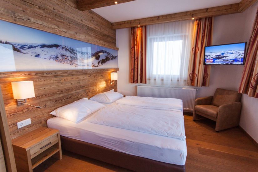 Schlafzimmer mit Doppelbett, Sessel und TV