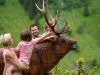 Kinder sitzen auf einem Hirsch - Wildlife Trail im Talschluss von Saalbach Hinterglemm