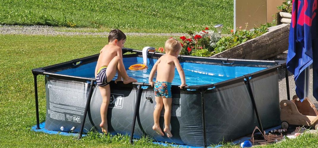 Zwei Kinder steigen gerade in ein Planschbecken