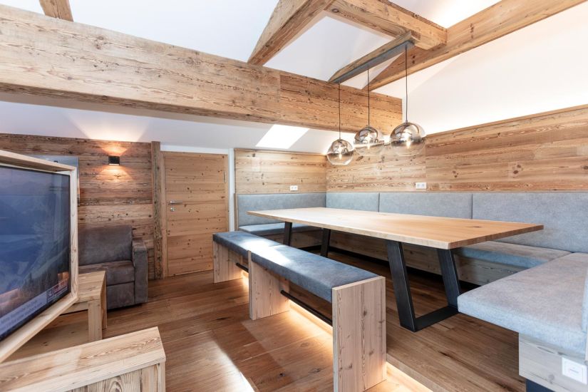 Große Sitzecke der Ferienwohnung 80 mit Eckbank, Esstisch, Holzverkleidung und Pendelleuchten