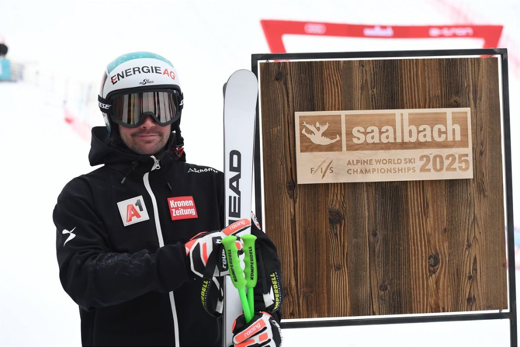 Vincent Kriechmeyer steht vor einer Holztafel mit der Aufschrift "Saalbach 2025 Alpine World Ski Championships"